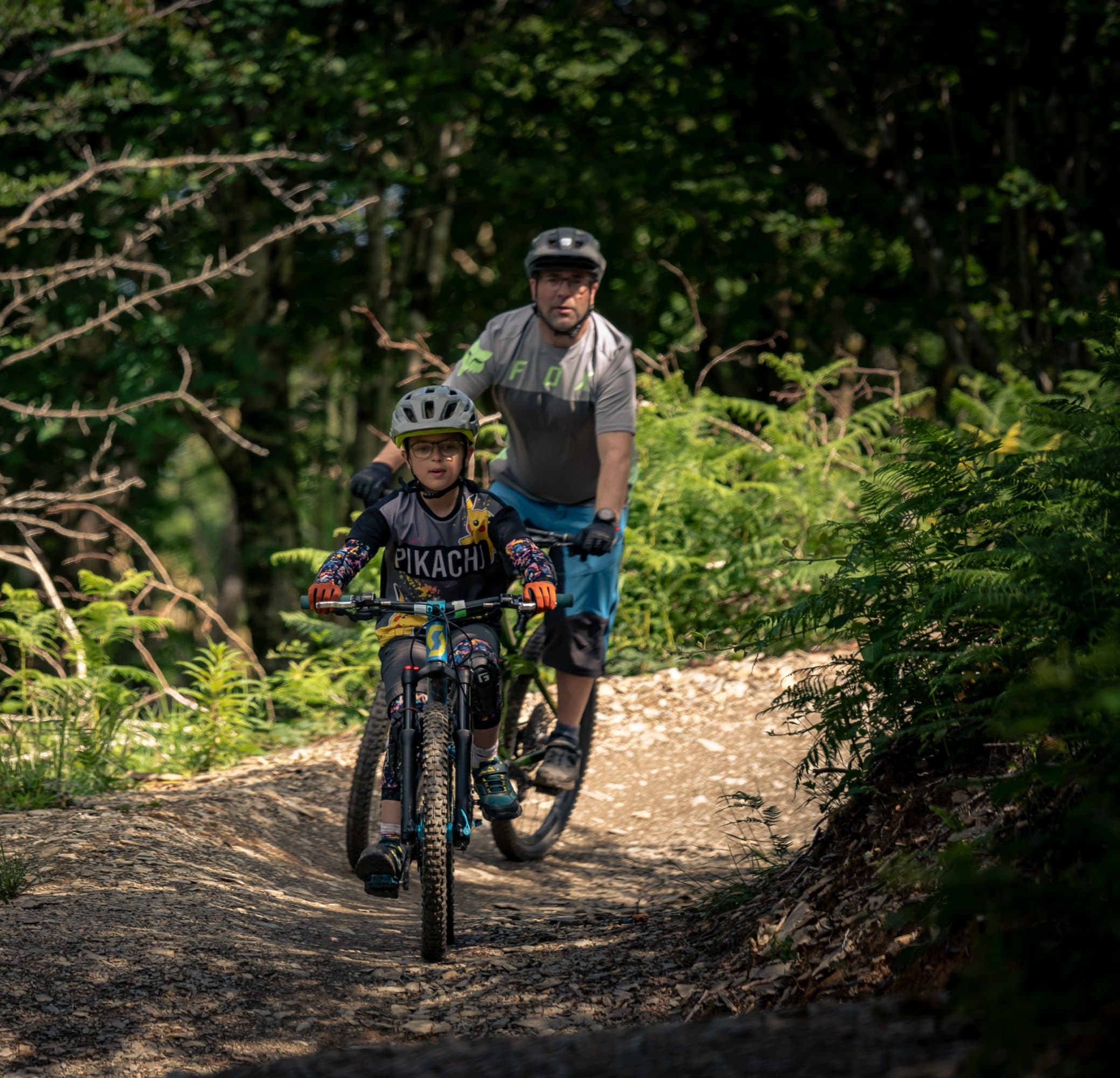 Adult riding behind a young child on a wide trail