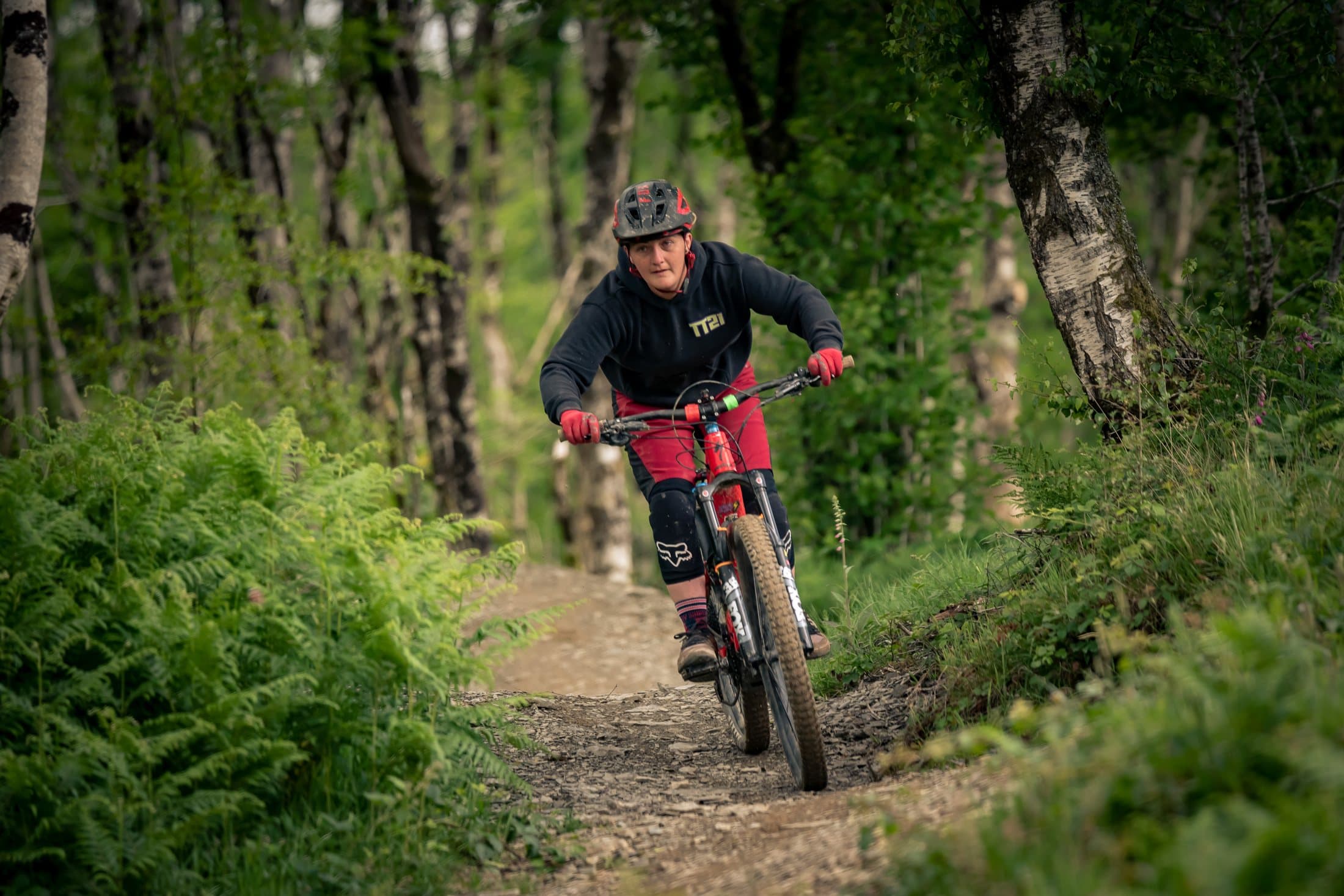 Rider rolling a green trail through open woodland