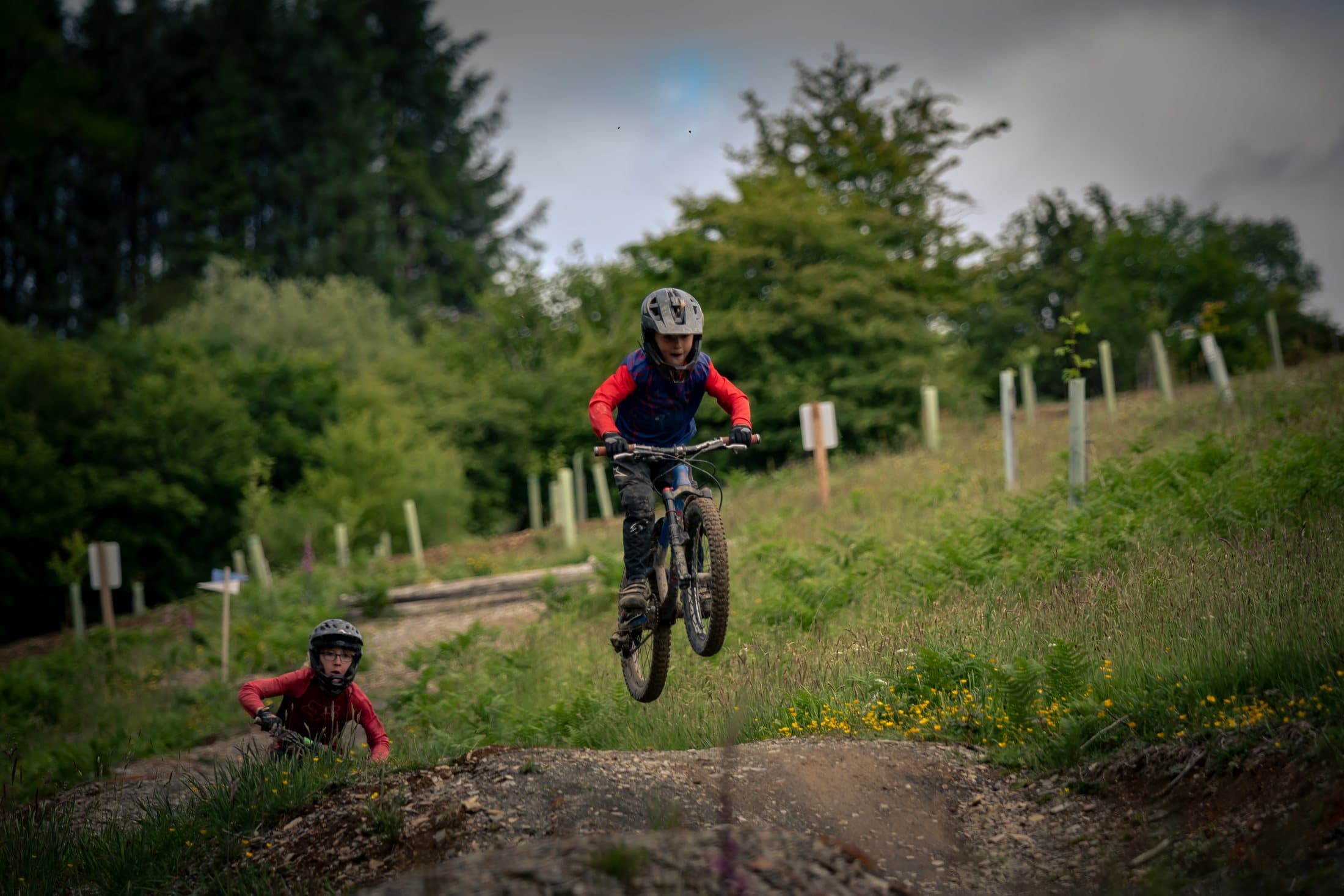 Rider in red jacket airborne on an open hillside jump