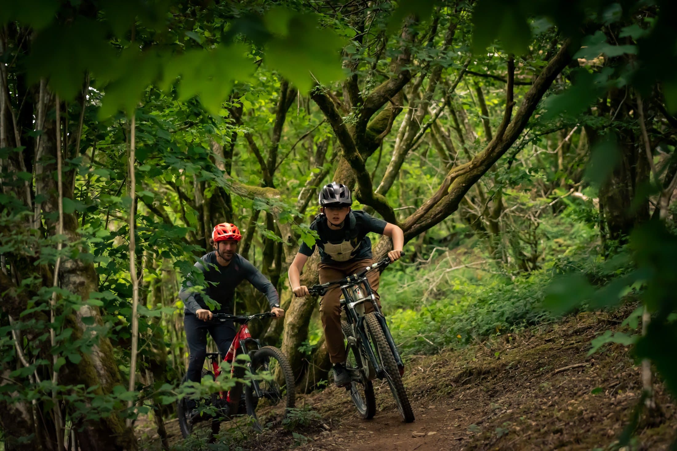 Two riders descending together through the trees