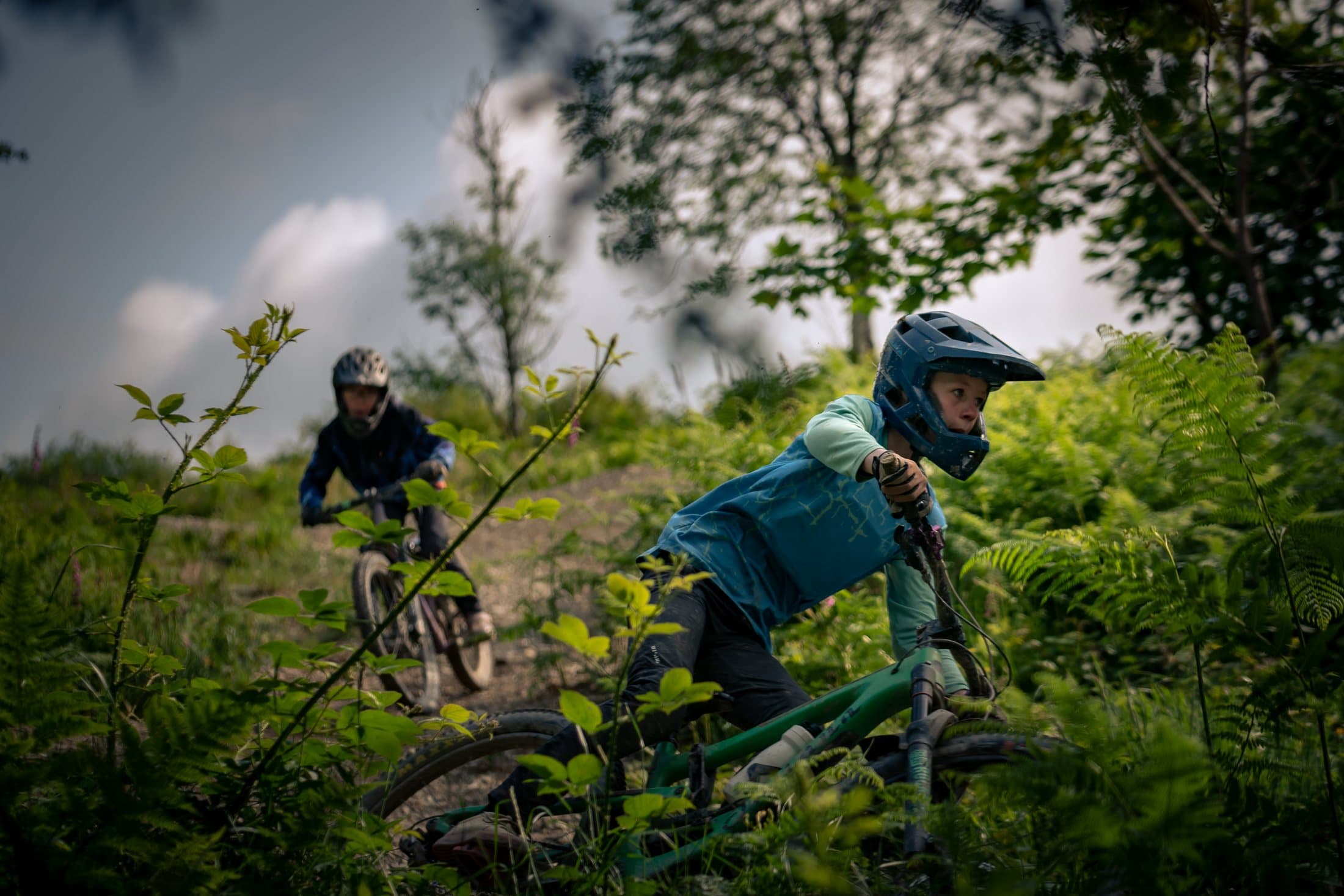 Two riders silhouetted against sky on an open ridge
